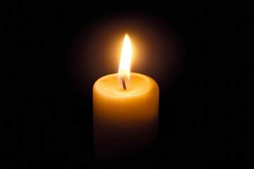 Glowing candle in darkness with bright flame and soft warm glow