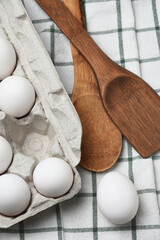 Country Kitchen Still Life. A carton of eggs on a kitchen towel with a wooden spoon and spatula.