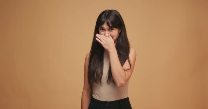 Hispanic woman feels disgust and holds nose on blue background