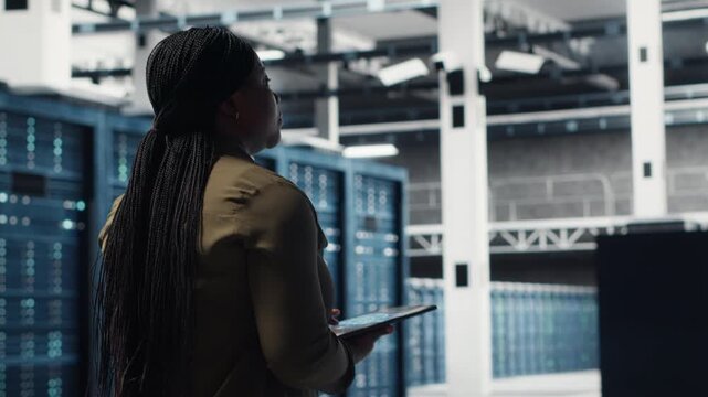 Woman walking through data center server rows, implementing advanced cooling and power management solutions. IT expert overseeing server farm, reducing energy consumption, camera B