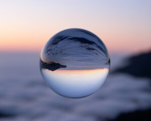 Crystal ball reflecting a beautiful sunset over a sea of clouds landscape
