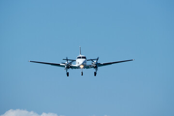 Small propeller plane flying in the blue sky on a sunny day. Twin-engine plane soaring through a clear blue sky.