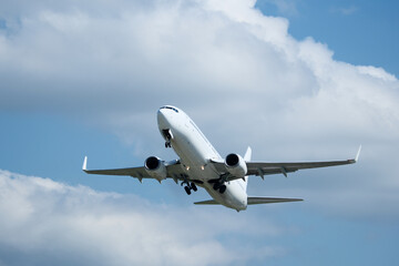 White plane climbing higher against the clouds. Airplane flying in the blue sky, take-off from airport