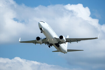 White plane climbing higher against the clouds. Airplane flying in the blue sky, take-off from airport