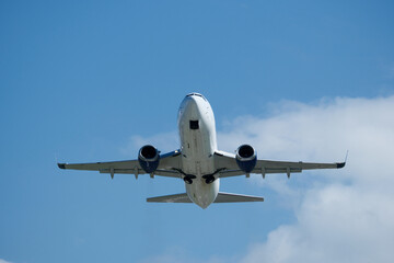 Obraz premium White plane climbing higher against the clouds. Airplane flying in the blue sky, take-off from airport