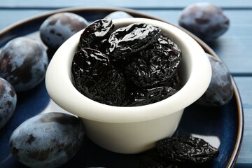 Dried prunes and fresh plums on blue wooden table, closeup