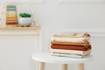 Stack of clean baby clothes on white table indoors, space for text