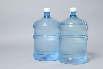 Cooler bottles with water on light grey background, closeup. Space for text