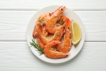 Tasty grilled shrimps served with rosemary and lemon on white wooden table, top view. Delicious seafood dish