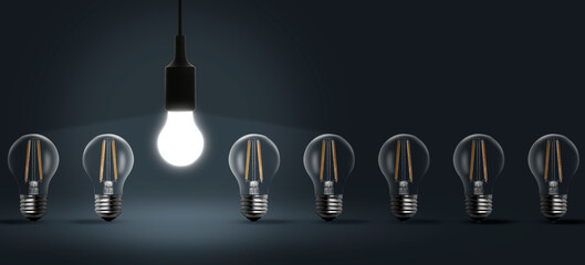 Concept of idea. One glowing light bulb among others on dark grey background. Banner design