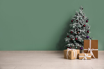Christmas tree with gift boxes near beige wall in room