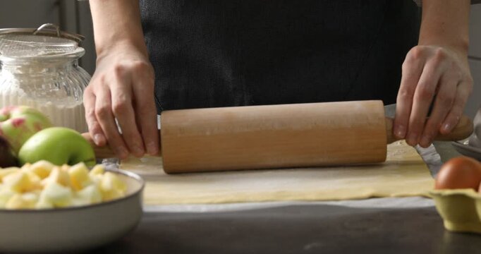 Woman making delicious apple strudel at grey table in kitchen, closeup