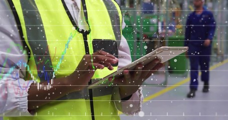 Tapping tablet worker wearing safety vest inspecting machines on factory floor, with data graphics