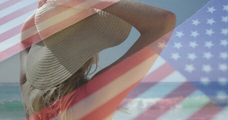 Fototapeta premium Gazing female beachgoer wearing straw sunhat and red bikini top at shoreline, with flag overlay
