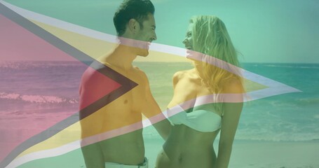 Smiling couple looking at each other wearing white swimwear on beach, with waves and flag overlay