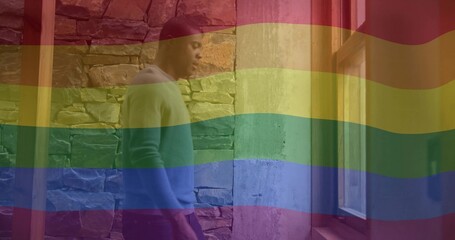 Gazing man wearing light sweater in stone hall with beams, window, rainbow overlay, copy space