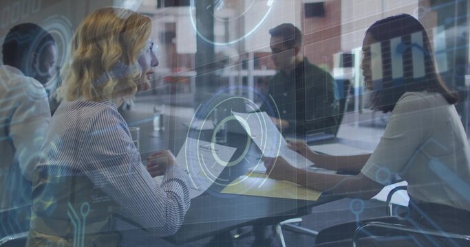 Collaborating colleagues in business attire analyzing HUD overlay in conference room, with laptops