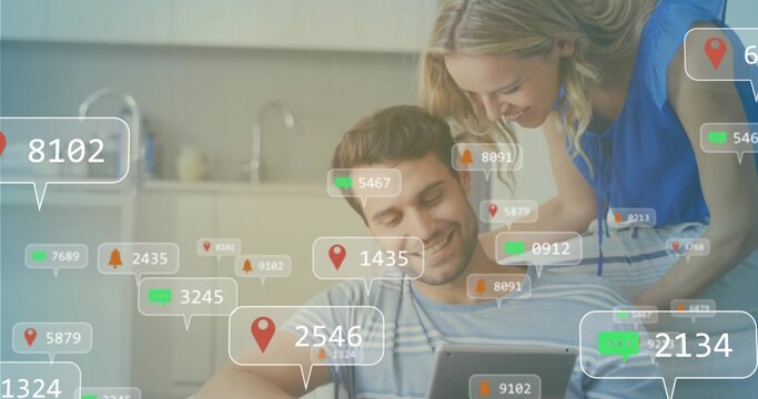 Tapping couple on sofa using tablet in open plan living room with floating notification icons
