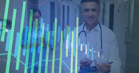 Monitoring doctor and nurse analyzing digital graphs in corridor, with stethoscopes and blue folder