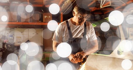 Grinding craftsman wearing overalls at workshop bench with angle grinder, sending sparks
