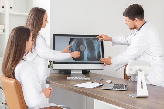 Doctors with magnifier studying x-ray image of lungs at hospital