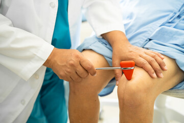 Asian doctor physiotherapist examining, massaging and treatment knee and leg of senior patient in...