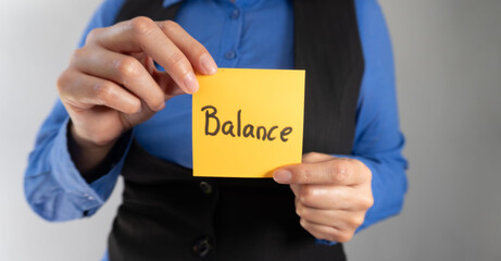 Businesswoman holding a sticky note with the word balance and showing it to the camera