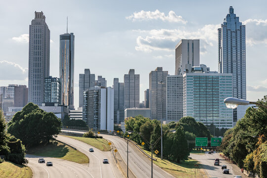 View of the Midtown, Downtown Atlanta Skyline showing several prominent buildings, highways, cars, light trials and hotels just prior to sunset.