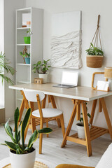 Interior of light living room with green houseplants, workplace and shelf unit