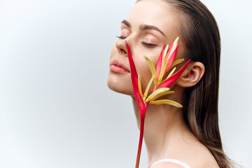 Serene beauty portrait with exotic flower on model's face, showcasing tranquility, elegance, and vibrant colors for fashion and wellness themes.