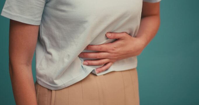 Young Hispanic woman feeling belly abdomen pain on blue background
