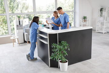 Medical interns with clipboard working at reception in clinic