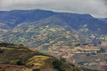 Fototapeta premium Terraced fields and patchwork farmland unfold beneath the imposing Andes near Kuelap fortress in Amazonas, Peru. Generations of local farmers have shaped this landscape.