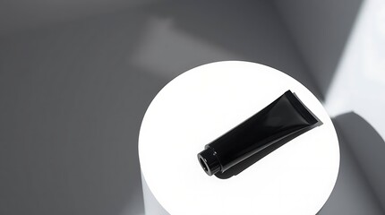 Sleek black cosmetic tube resting on a bright white surface with modern shadows for luxury beauty product ads