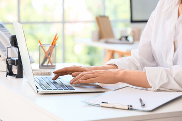 Young secretary working  with laptop in office, closeup