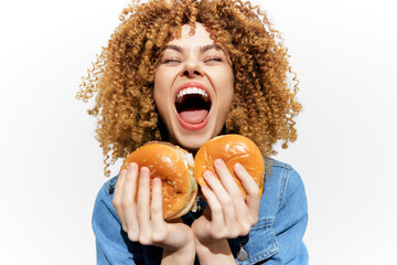Happy young woman with curly hair joyfully holding two burgers, showcasing excitement and love for fast food in vibrant colors