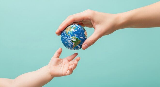 Adult hand passing a small Earth globe to a child's reaching hand. Concept of inheritance, future generations, and environmental responsibility.