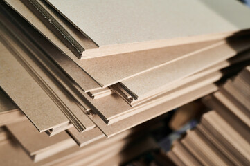 Stacks of thick paperboard ready for transformation into sustainable cardboard boxes at a manufacturing facility
