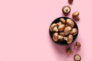 Bowl with fresh raw mushrooms on pink background