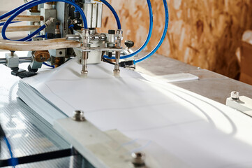 Innovative pneumatic paper sheet feeder streamlining production process in a busy workshop setting