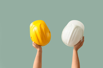Male hands holding hardhats on green background