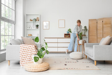 Female interior designer putting plant in living room