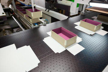 Production of decorative cardboard boxes on the conveyor in a packaging factory showcasing vibrant design elements and efficient workflow