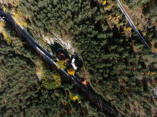 Aerial view of a rustic wooden train station and vintage rail cars amid autumn foliage in Tara, Serbia. g.