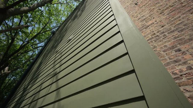 Wide view of green siding of the house wall with modern panels, providing classic exterior look on sunny day. move camera view