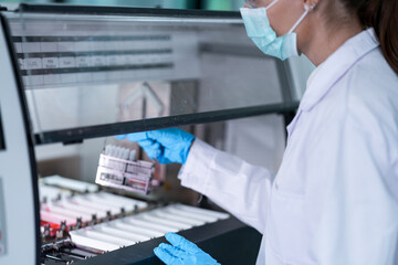 A clinical laboratory scientist loads a sample rack into a high-throughput chemistry analyzer. This automated system is used for quantitative analysis of various analytes in patient serum.