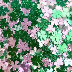 Closeup of green and pink clover shaped glitter confetti