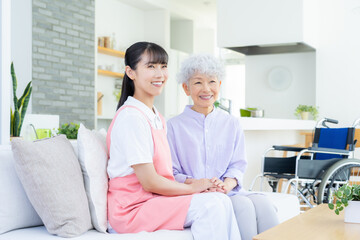 Obraz premium 高齢者を介護する若い女性介護士