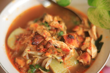 Bowl of Authentic Soto Ayam with Shredded Chicken and Aromatic Spices