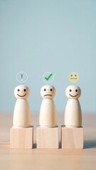 Three wooden figurines stand on blocks, each with a different emoticon depicting satisfaction levels against a light blue backdrop